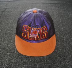 Up for sale 1990s Phoenix Suns cap Used cap, Show sign of wear, Minor stain on cap, Overall in good vintage condition (Please refer last picture) Size on cap: Not available, Adjustable strap Feel free to message me for measurements if you are not sure it will fit. Tag Label: Not available Feel free to e-mail me about any questions you have Ships out within 1-3 business days Please review our shop policies before make an order Feel free to visit my shop Thank you! 90s Style Adjustable Trucker Hat, 90s Style Adjustable Trucker Hat Baseball Cap, Throwback Trucker Hat For Sports Events, Retro Snapback Baseball Cap For Fans, Throwback Trucker Hat For Streetwear, 90s Style Trucker Hat, 90s Style Adjustable Baseball Cap Snapback Hat, 90s Style Baseball Cap For Streetwear, Retro Snapback Baseball Cap For Fan Merchandise