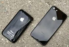 two iphones sitting side by side on the ground next to each other, one black and one gray