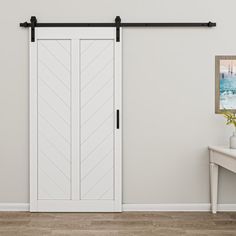 an empty room with a white door and black hardware on the sliding barn door,