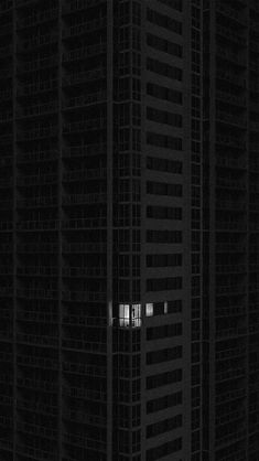 a tall building with two windows in the middle of it's dark night sky