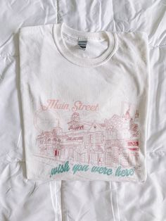 Main Street Greetings Graphic Tee Say hello to the Greetings Collection! A collection of tees so nostalgic looking that you'll think you found it in the back of your local vintage shop. We made sure to include every detail of each land that only a true fan of the parks would pick out. It's buttery soft, the perfect gift for a friend, and can be styled both oversized with biker shorts or more fitted with your favorite pair of sweats. What you will get: A soft, lightweight shirt with the right amo Senior Merch, Theme Park Shirts, Thrift Inspo, Sorority Merch, Graphic Tee Vintage, Main Street Usa, Shirt Design Inspiration, Graphic Tees Vintage, Vintage Shop