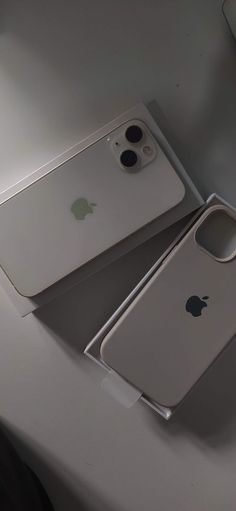 two iphones sitting on top of a table next to each other, one is silver and the other is white