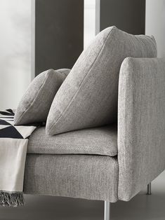 a gray couch with pillows on it and a blanket draped over the armrests