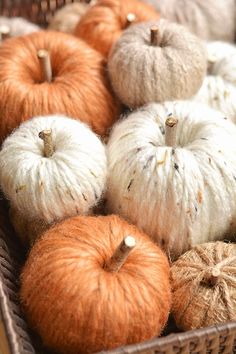 several balls of yarn sitting in a basket with pumpkins on the floor next to them