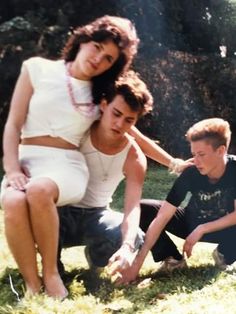 three people sitting in the grass together