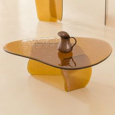 a glass table with a brown vase on top