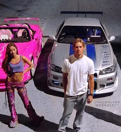 a man standing next to a woman in front of a pink car and a white sports car