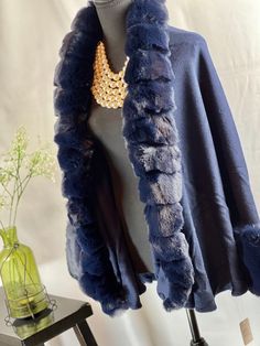 Upgrade your winter wardrobe with this chic navy blue cape. Made from a luxurious blend of wool and acrylic, it features a stylish faux fox fur trim that wraps around the neck and cascades down the front for added warmth. The open front style adds an element of sophistication to this piece. This cape exudes elegance with its faux fur trim that gives it a high-end look. The two-tone gradient color adds a unique touch, making it the perfect accessory to wear with jeans or leggings for any occasion. The voluminous faux fur adds a layer of style and is a must-have for those cold winter months. Not only is this cape perfect for fashion outings, but it's also ideal for casual wear, holiday festivities, shopping, dates, and any evening party. You can even wear it to your prom or as a bridal cover Elegant Blue Shawl For Fall, Elegant Blue Fall Shawl, Blue Winter Outerwear For Evening, Elegant Winter Shawl Outerwear, Elegant Winter Capelet, Elegant Evening Winter Capelet, Luxury Blue Winter Peacoat, Elegant Evening Capelet For Winter, Elegant Winter Shawl Cape