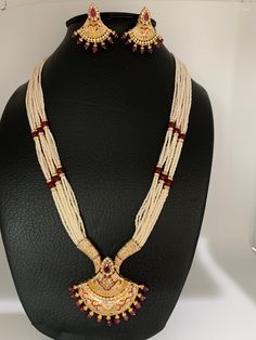 Small Pearl Rani Haar with CZ Red Stone Pendent with matching earringsColor : Pearl WhiteSize : Mala Length : Approx 22 Inches; Earrings Length : 1.5 InchesStones : Red Stone AD Pearls Rani Haar, Pearl Mala, Red Stone, Indian Jewelry, Pearl White, Statement Necklace, Beaded Necklace, Stone, Red