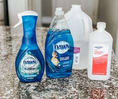 three bottles of dawn and powerwash on a counter top with other cleaning products nearby