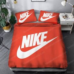 a bed with a red comforter and two pillows that have white nike logos on them