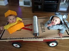 two babies are sitting in a wagon made out of wood and construction equipment, with the baby on top