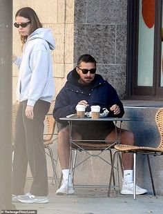 a man and woman sitting at a table with coffee