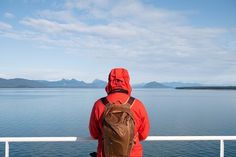 a man with a backpack is looking out over the water from a boat on a sunny day