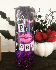 a purple glittered cup with lipstick on it next to a white vase and red rose