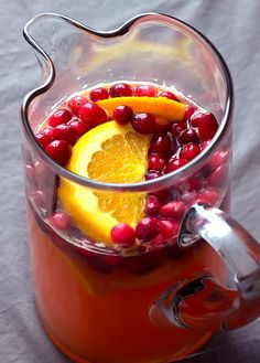 a pitcher filled with orange slices and cranberries