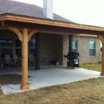 an outdoor covered patio with a grill in the background