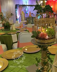 an elaborate birdcage filled with flowers and greenery on top of a table