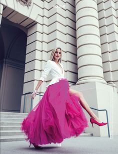 a woman in a white shirt and pink tulle skirt is posing on some steps