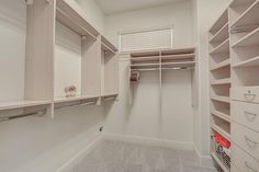 an empty walk in closet with white shelving