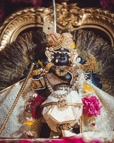 an idol is displayed in front of a gold and white backdrop with flowers on it