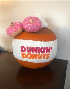 two donuts are sitting on top of a dunkin'donuts painted pumpkin