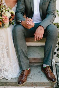 a bride and groom sitting on steps holding hands