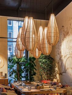 an indoor dining area with wooden tables and chairs, hanging bamboo lamps above the table