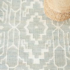 a straw hat sitting on top of a rug next to a blue and white pattern