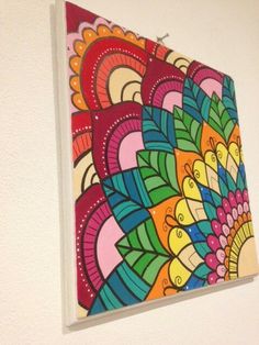 a colorful painting hanging on the wall next to a white wall with a light switch