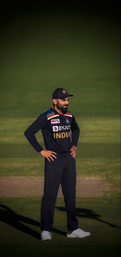 a man standing in the grass with his hands on his hips wearing a baseball uniform