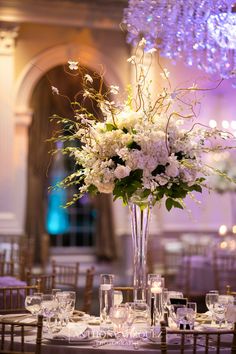 a tall vase filled with white flowers on top of a table