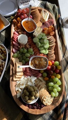 a platter filled with cheeses, crackers, and fruit on a table