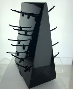 a black sculpture with many sticks sticking out of it's sides on a white surface