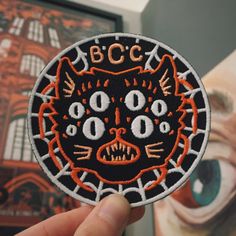 a hand holding up a patch with an image of a cat on it's face