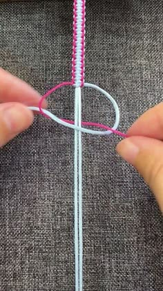 someone is stitching the end of a piece of fabric with pink thread on it