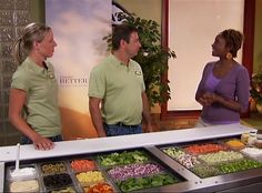 two women and a man standing in front of a salad bar