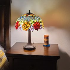 a table with a lamp on top of it next to a night stand and a candle