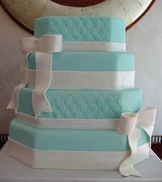 a blue and white wedding cake sitting on top of a table next to a mirror