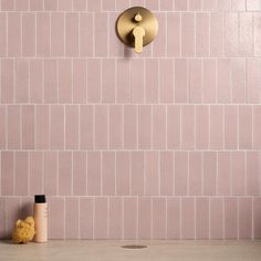 a bathroom with pink tiles and a gold toilet paper dispenser on the wall