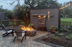 an outdoor fire pit in the middle of a backyard with patio furniture and string lights