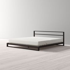 an empty bed frame on the floor in a room with white walls and hardwood floors