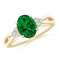 a ring with an oval green stone and three diamonds on the band, set in yellow gold