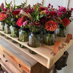 several jars filled with flowers sitting on top of a wooden table