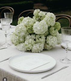 the table is set with white flowers and silverware