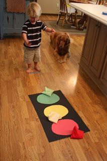 a young boy standing next to a dog on top of a hard wood floor in a kitchen