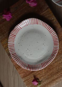 a white plate sitting on top of a wooden cutting board next to pink flower petals