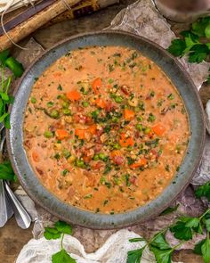 a bowl of soup with carrots, celery and peas on a table