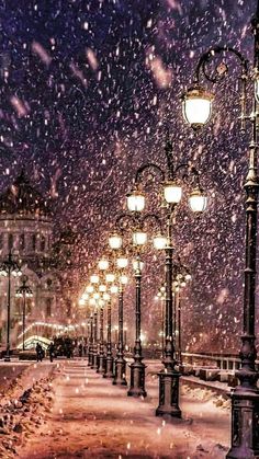 a snowy night with street lights and snow falling on the ground