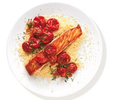 two salmon fillets with tomatoes and parmesan on a white plate against a white background